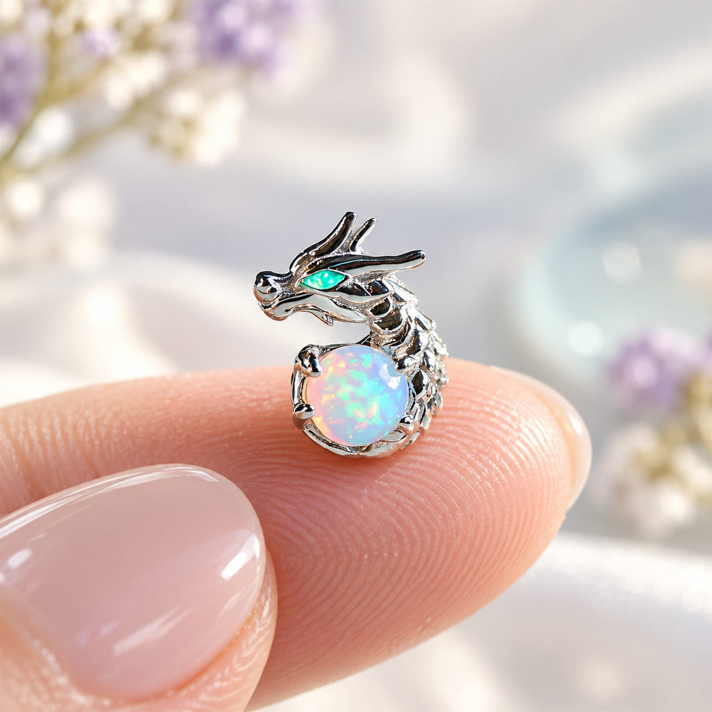 Boucles d'oreilles Dragon Mopaline, posée sur le bout du doigt pour montrer la petite taille