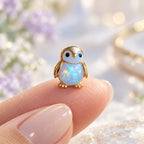 Boucles d'oreilles Pingouin Mopaline, posée sur le bout du doigt pour montrer la petite taille
