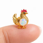 Boucle d'oreille Poule Opale posée sur le bout du doigt pour montrer sa petite taille